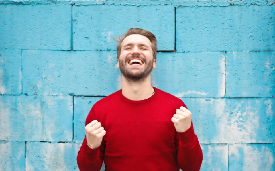 Filipino man in a red shirt cheering after a slot bonus round on 218PLUSPH