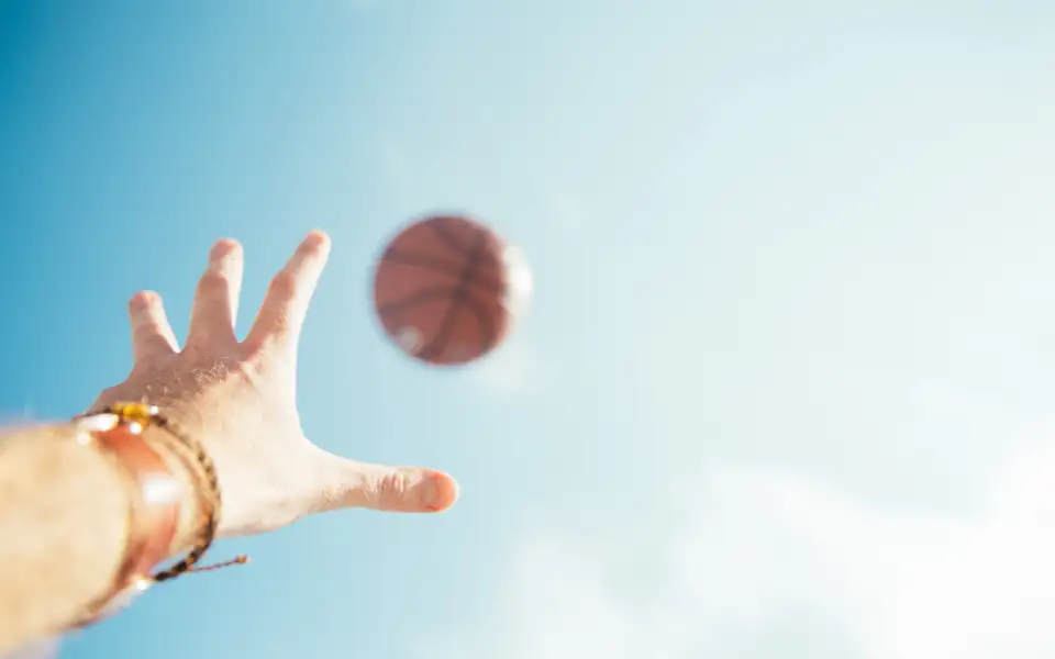 Hand reaching for a basketball against the sky, illustrating 218PLUSPH sports betting on PBA and NBA games